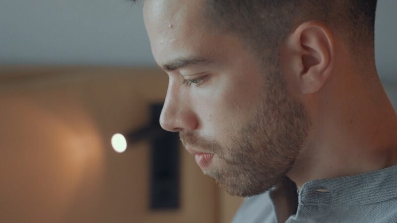 Close-up of a man in his 40s looking down with a serious expression, suggesting introspection or concern