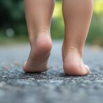 Close-up of a child walking barefoot on a paved path, with visible low arches