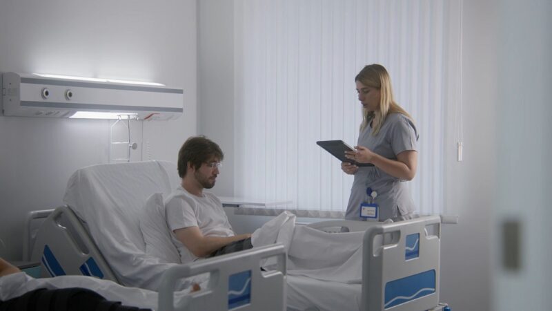Nurse with a tablet providing orientation and onboarding information to a patient in a hospital room