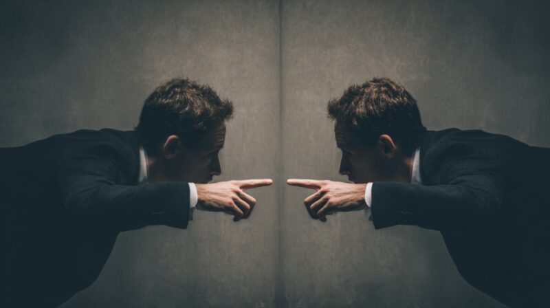 Man in a suit pointing at his reflection in a mirror, symbolizing self-accountability