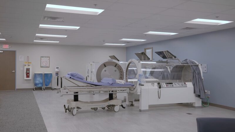 Clinical treatment room with transparent hyperbaric oxygen therapy chambers and patient beds prepared for HBOT sessions