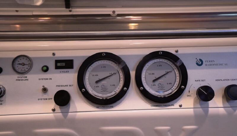 Close-up view of hyperbaric oxygen chamber control panel with pressure gauges, system indicators, and adjustment knobs