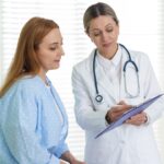 A doctor reviews primary care notes with a woman during a routine clinic visit