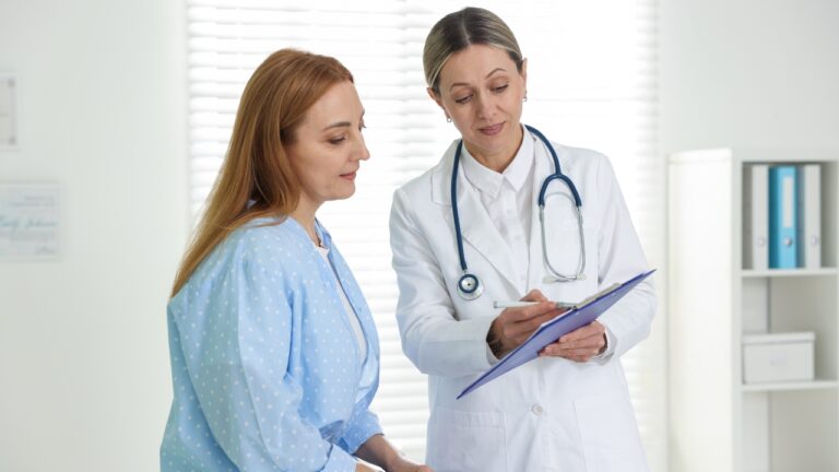 A doctor reviews primary care notes with a woman during a routine clinic visit