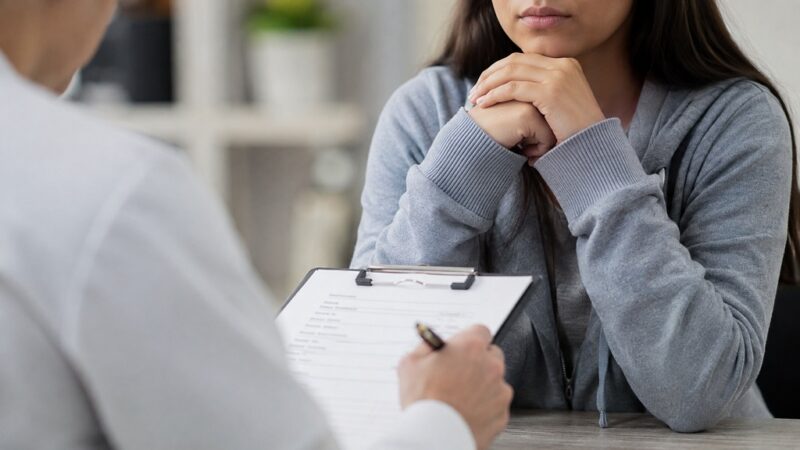 Healthcare professional conducting a confidential mental health and online safety screening with a young patient