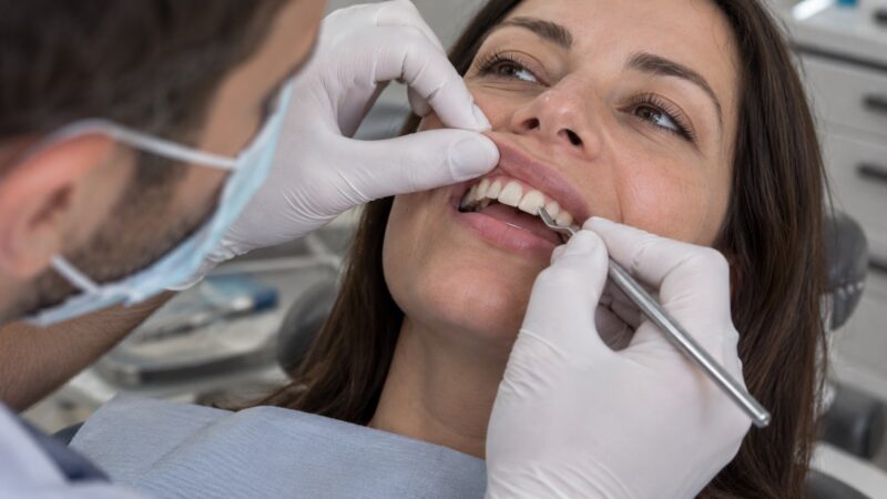 Dentist examining and treating a small chipped front tooth with a dental instrument.