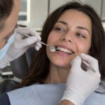 Dentist examining a patient’s front teeth with dental instruments.